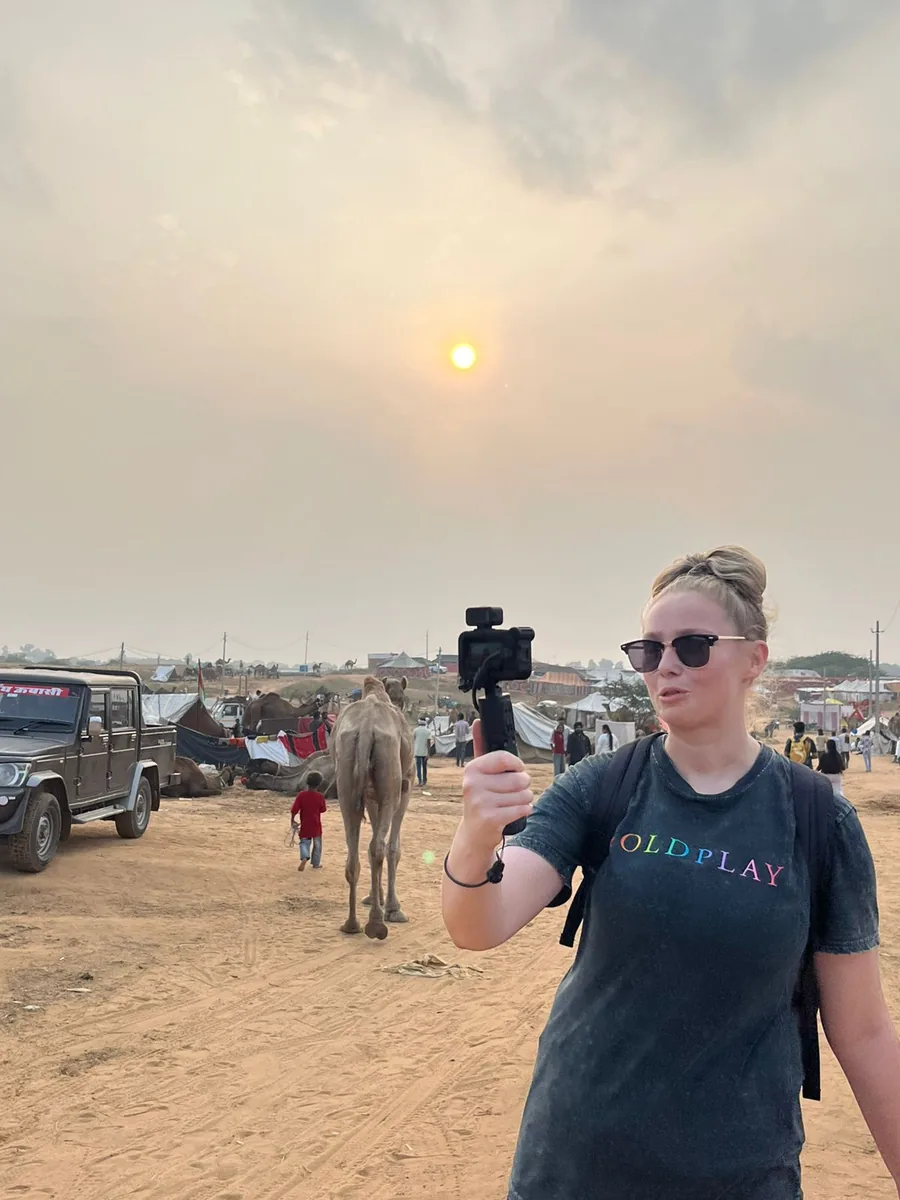 A visitor photographs camels at the Pushkar Camel Fair