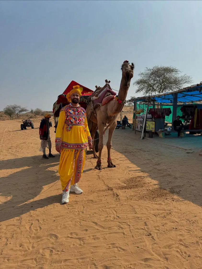 A traveller rides a camel in the desert near Pushkar