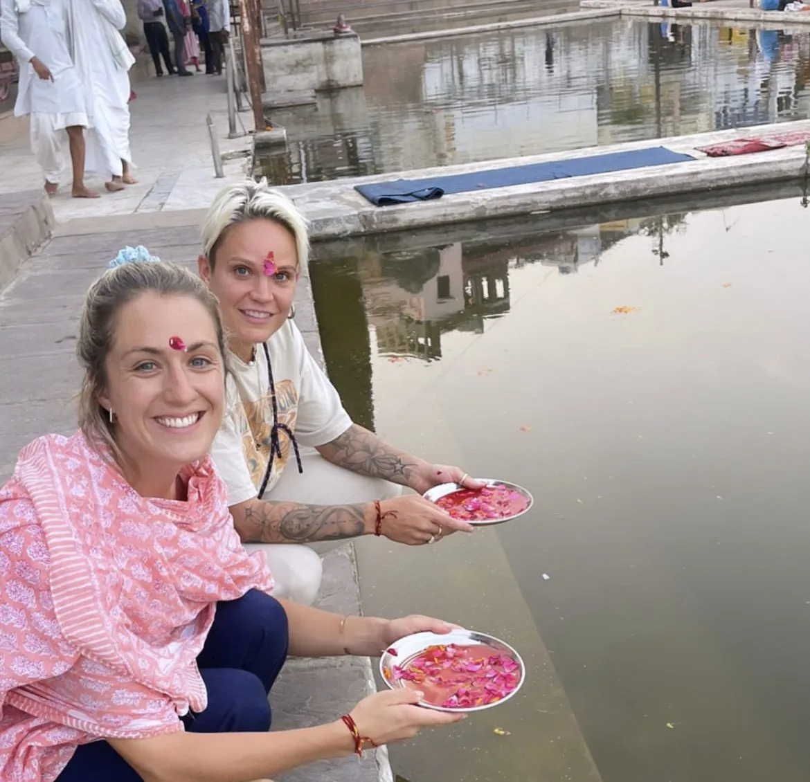 Visitors hold flower offerings beside the sacred lake