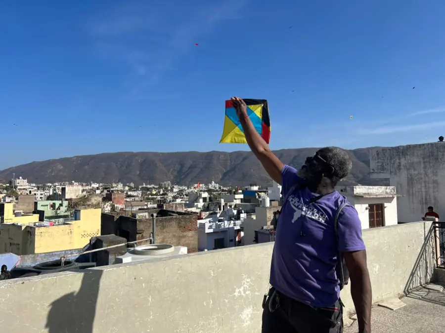 A visitor flies a kite from a rooftop overlooking Pushkar